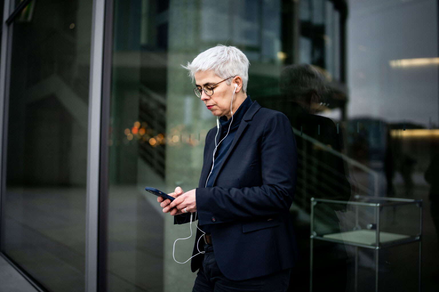 Ulle Schauws steht vor einem Glasgebäude und hält ein Smartphone in den Händen
